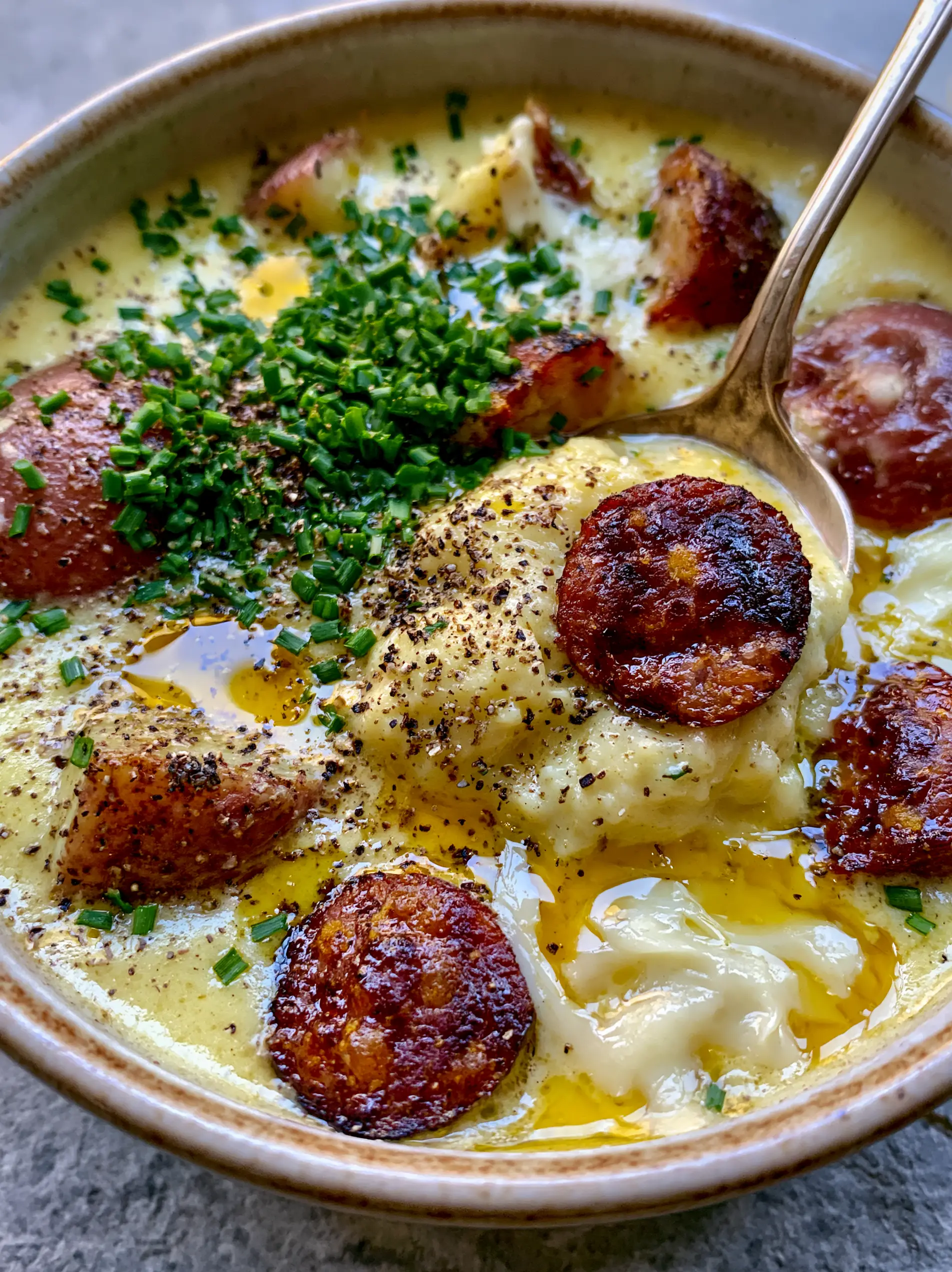 Extreme close-up of velvety kielbasa potato soup showing seared sausage edges and golden butter pools. (kielbasa potato soup)