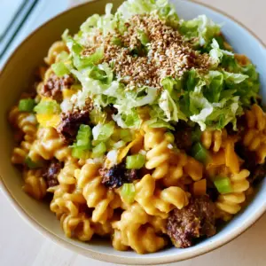 Close-up of Big Mac pasta salad showing the glossy pale orange sauce coating rotini pasta and chunky seared ground beef.